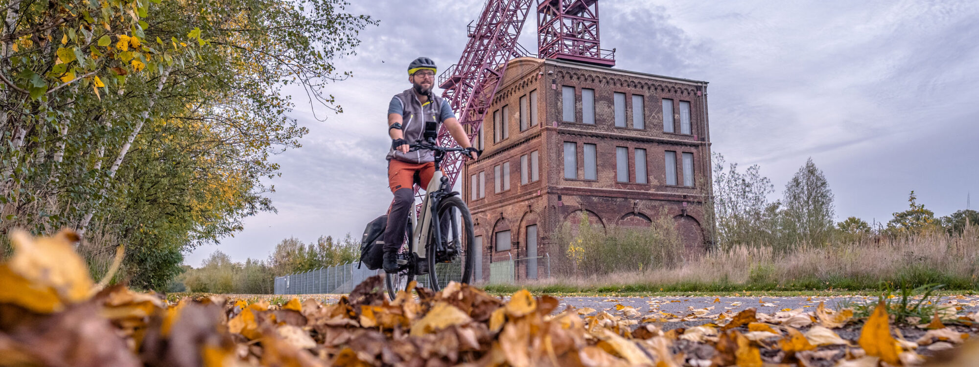 Das Foto zeigt einen Radfahrer beim Bahntrassenradeln im Herbst auf der HOAG-Trasse in Oberhausen vor der Zeche Sterkrade